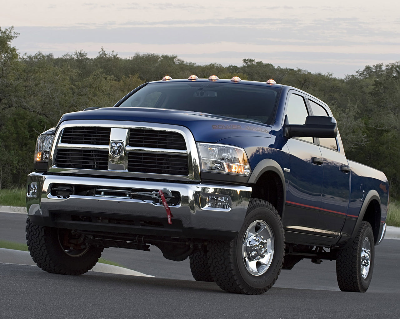 Blue Dodge 3500 Power wagon truck parked on driveway with trees and the sky in background