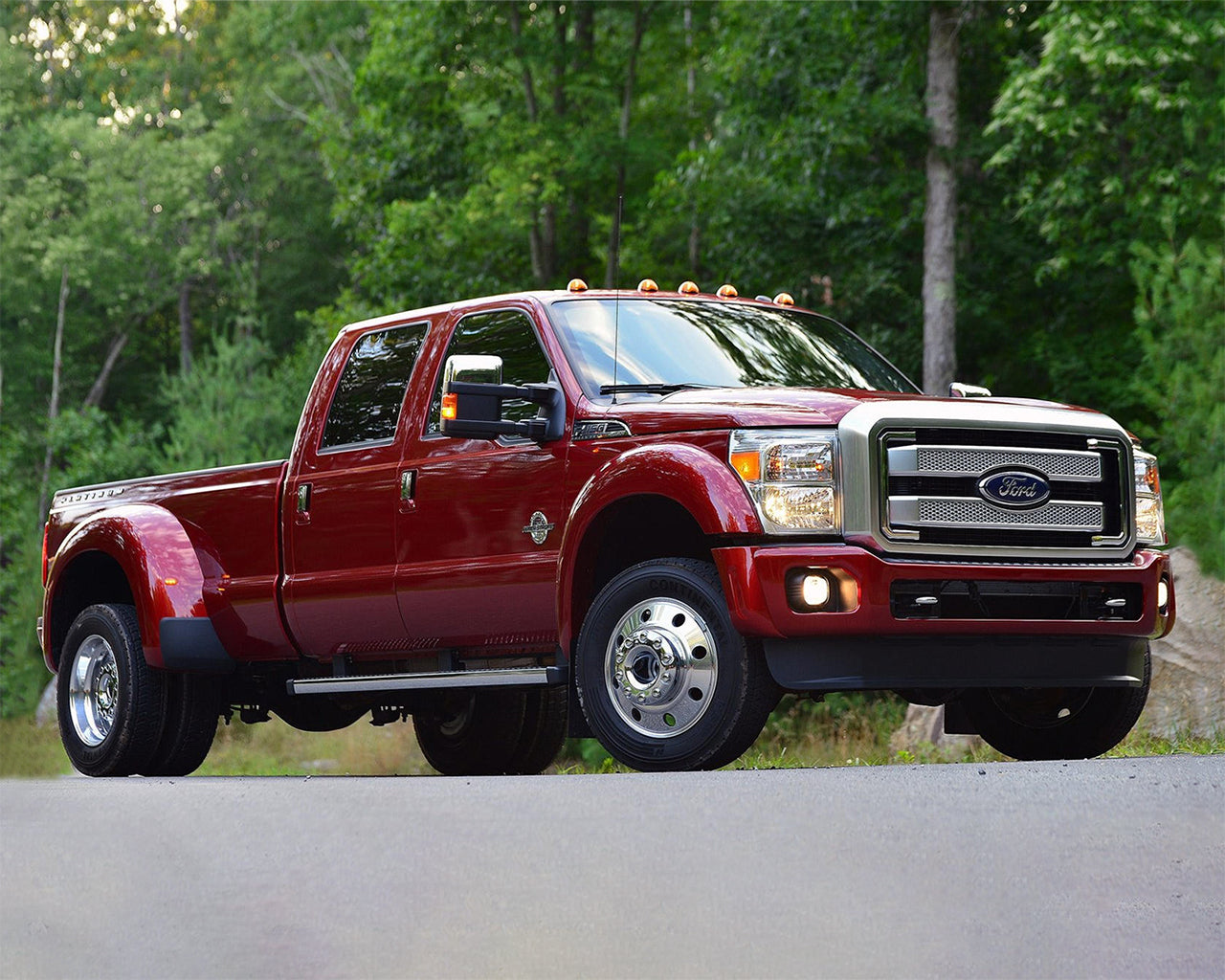 Red Ford Super Duty F-450 parked on the road with trees in the background