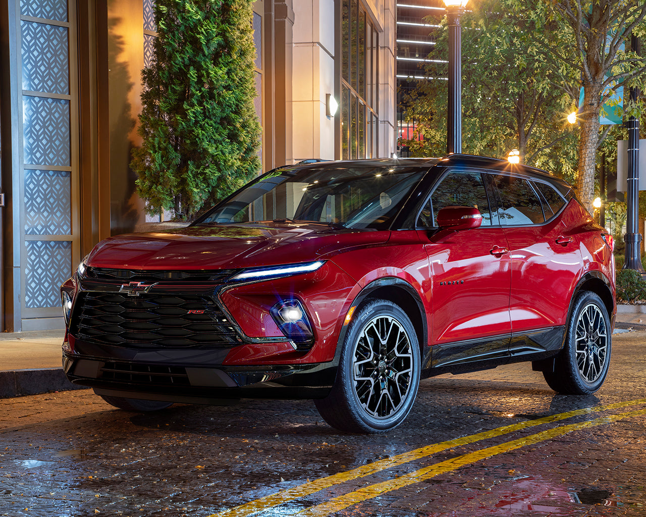 Red Chevrolet Blazer parked next to a building and wet road
