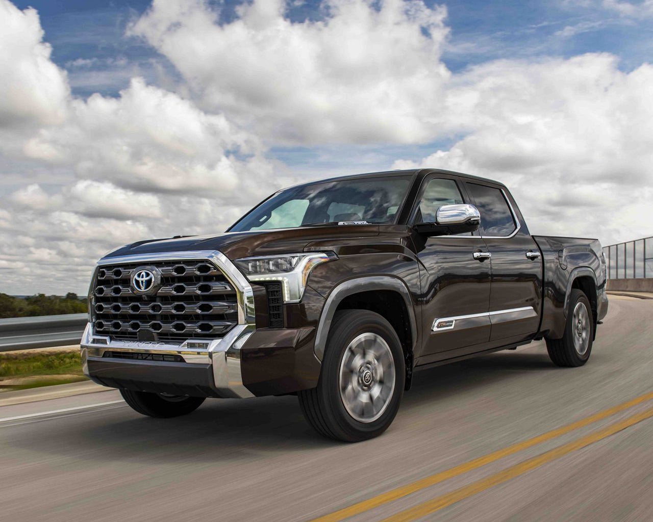 Brown Toyota Tundra driving on the road blue sky with clouds in the background