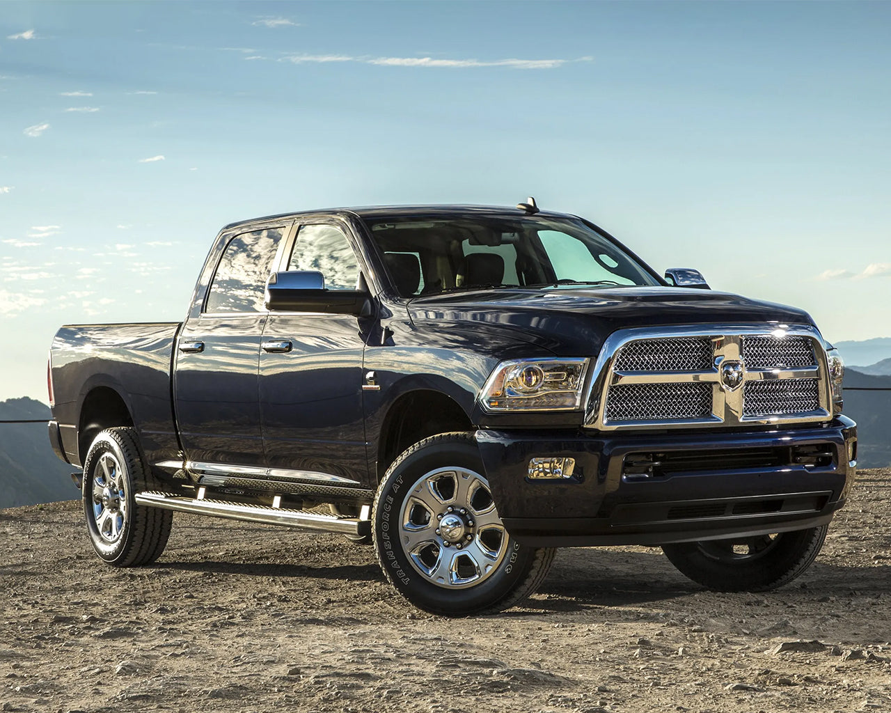 Black Dodge Ram 2500 parked on a dirt path with clouds in the sky in background