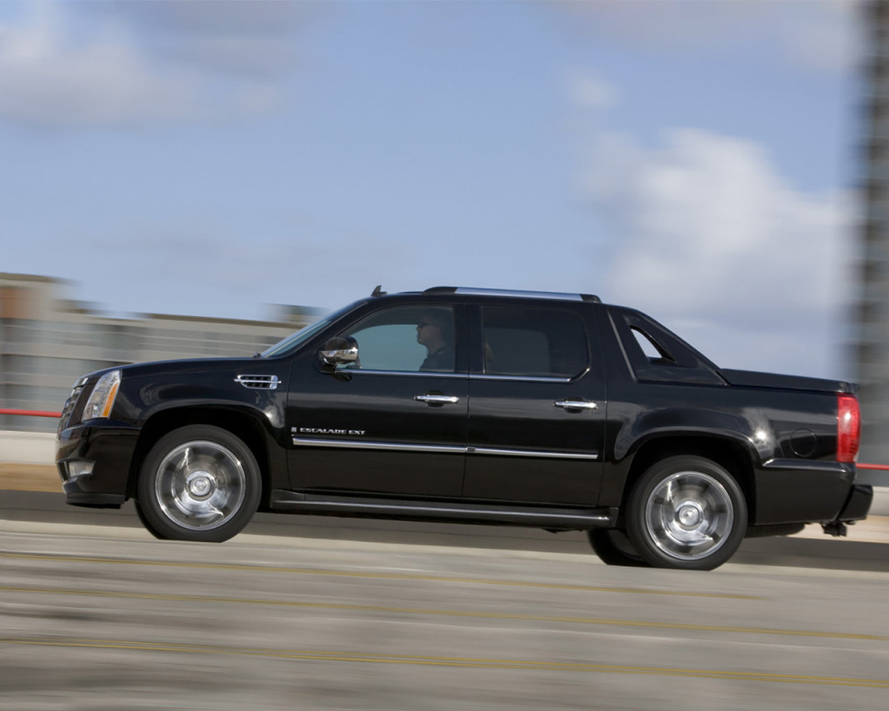 Black Cadillac Escalade EXT Truck driving fast on the freeway