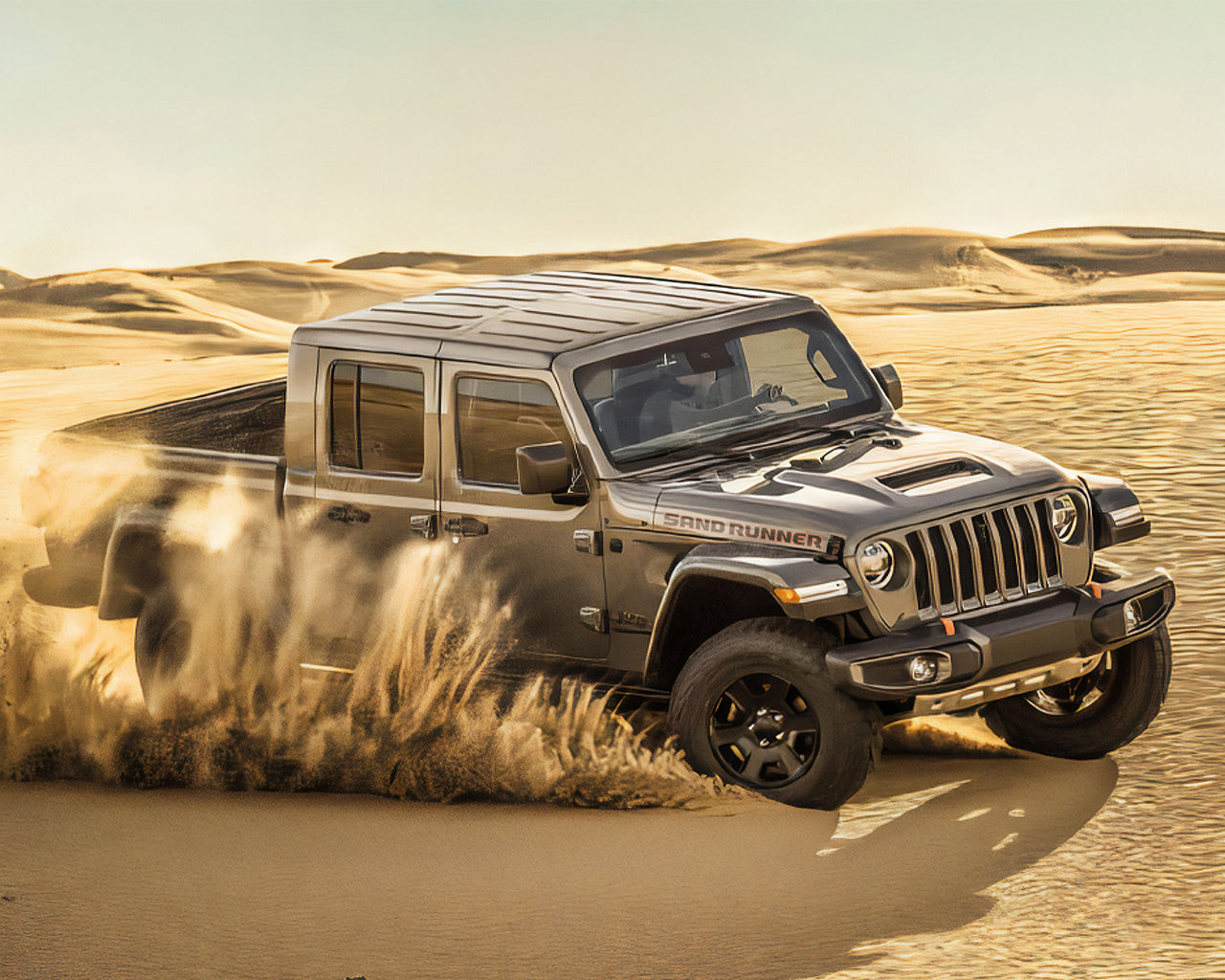Grey Jeep Gladiator driving through sand