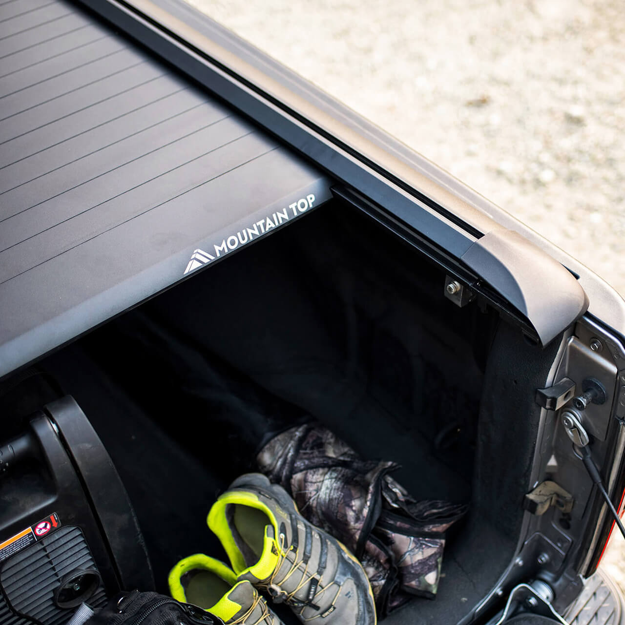 Detailed closeup of Mountain Top Retractable Tonneau Truck bed cover slightly open showing camping equipment